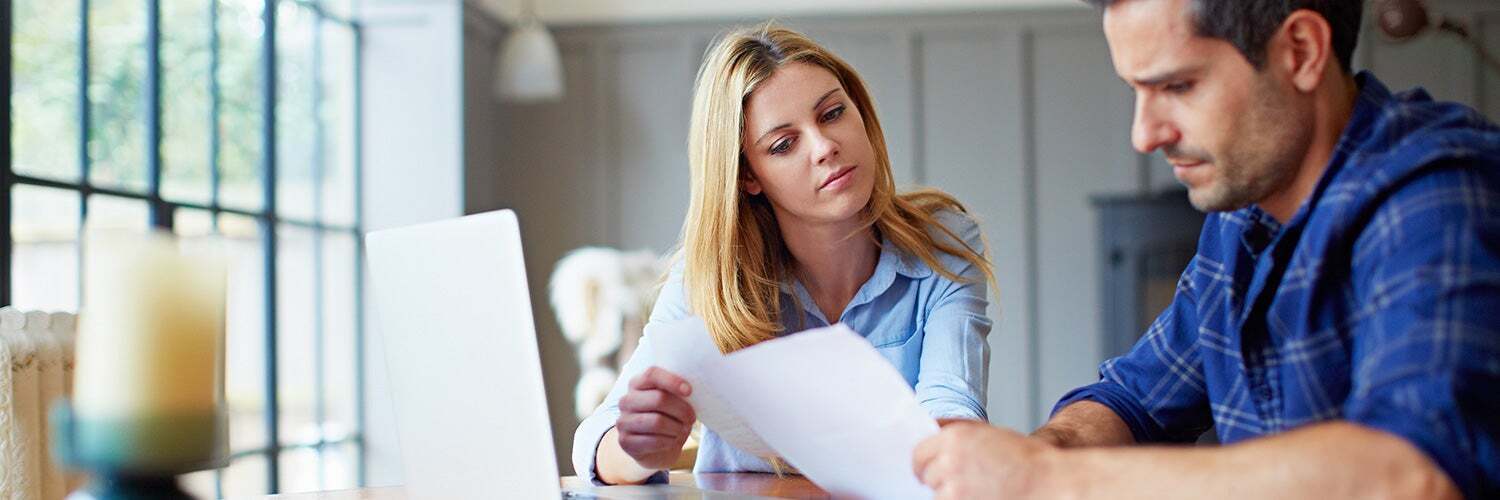 couple reading paperwork in their dining room<br />
