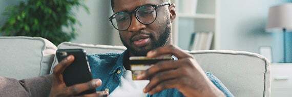 Man holding credit card and cell phone.